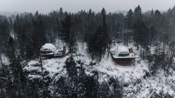 Two geodesic dome cabins in a snowy forest.