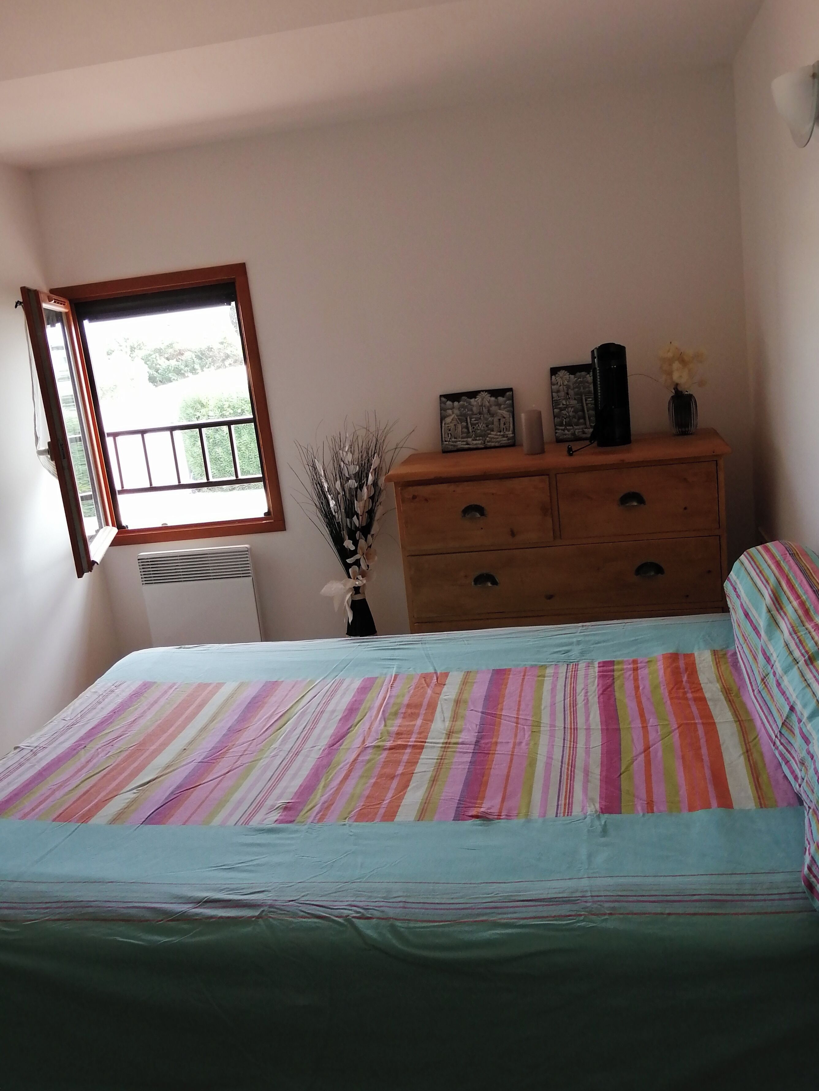 Ein Schlafzimmer mit einem Bett, einem Schminktisch, einem Fenster und einer Heizung.