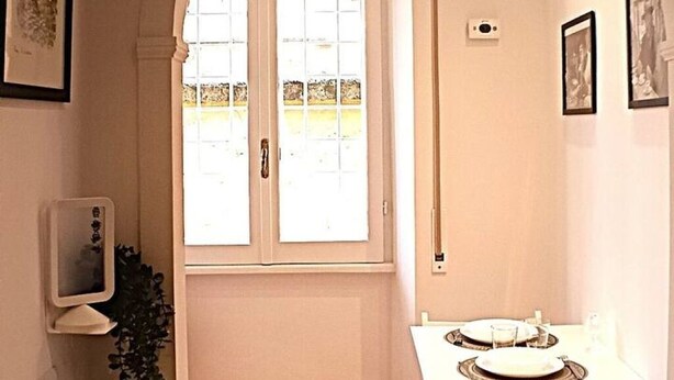 Une salle de bain avec un lavabo blanc, un miroir et une fenêtre donnant sur un jardin.