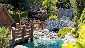 Ein Garten mit einer Holzbrücke, einem Steinkanal und einem kleinen Wasserfall.