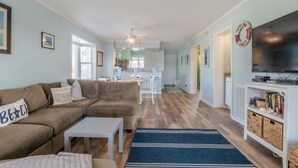 A living room with a sofa, coffee table, and a TV on a stand. - Sea The World- Private Access to Beach! (Carolina Beach)