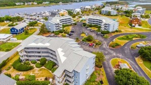 A coastal residential area with multiple buildings, a marina, and a curved road. - Sea The World- Private Access to Beach! (Carolina Beach)