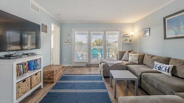 A living room with a television, sofa, coffee table, and a blue rug. - Sea The World- Private Access to Beach! (Carolina Beach)