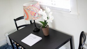 Una mesa negra con una lámpara colorida, una orquídea en maceta y un manual para huéspedes.