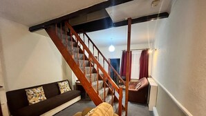 A living room with a staircase, a sofa, and a chair. - Spacious Four-bedroom House With Garden in Wembley (Wembley)
