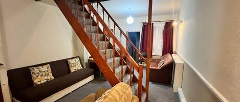 Una sala de estar con una escalera, un sofá y un sillón.