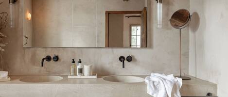 Une salle de bain avec un grand miroir, deux lavabos et une serviette accrochée au mur.