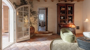 A room with a wooden ceiling, a large cabinet with glass doors, a green armchair, and a potted plant. - Hotel Vestige Binidufà (Ferreries)