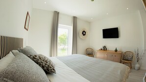 A bedroom with a large bed, a flat-screen TV, a dresser, and a window with curtains. - Quinta da Pisilveira (Loulé)