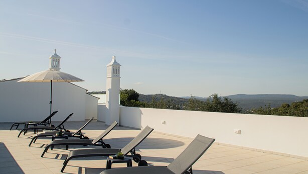A rooftop terrace with sun loungers and a large umbrella, overlooking a scenic landscape with hills. - Quinta da Pisilveira (Loulé)