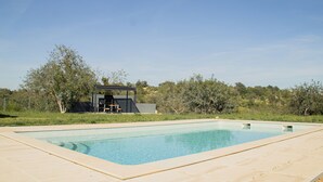 A rectangular swimming pool with a tiled edge, surrounded by a light-colored patio area. - Quinta da Pisilveira (Loulé)