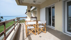A balcony with a wooden table and chairs, a ceiling fan, and a view of the ocean.