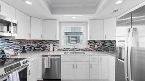 Una cocina moderna con armarios blancos, un refrigerador de acero inoxidable y un salpicadero de azulejos.
