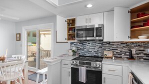 Una cocina moderna con armarios blancos, un microondas de acero inoxidable y un horno negro.