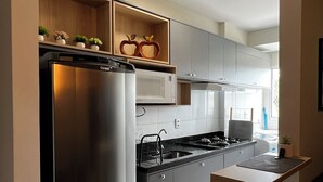 A modern kitchen with stainless steel appliances, wooden cabinets, and a built-in microwave. - New and Cozy Apartment! Close to the Mother Bonifácia Park and Santa Rosa Hospital. (Jardim Mariana Cuiabá)