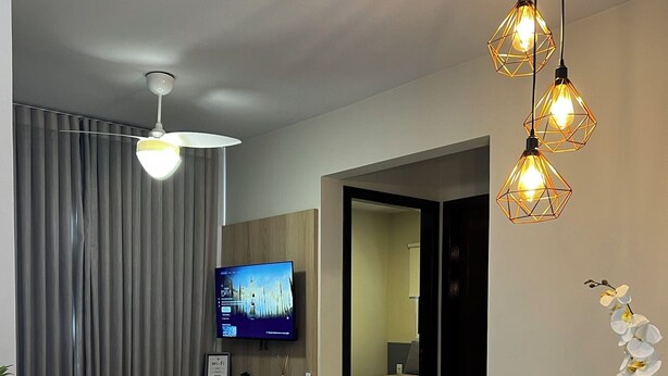 A modern living room with a dining area, a flat-screen TV, and decorative lighting. - New and Cozy Apartment! Close to the Mother Bonifácia Park and Santa Rosa Hospital. (Jardim Mariana Cuiabá)