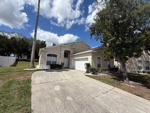 A single-story house with a garage, a driveway, and a well-maintained lawn. - Executive Vacation Home Near Disney Perfect for Large Families! (Davenport)