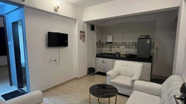 Ein modernes Wohnzimmer mit einer Couch, einem Couchtisch und einem an der Wand befestigten Fernseher.