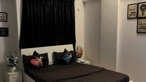 Ein Schlafzimmer mit Bett, Nachttisch, Wandsteckdose und gerahmten Motivationssprüchen.