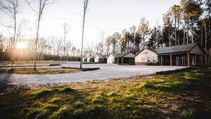 A building with multiple rooms and a covered parking area, surrounded by trees and a grassy field. - Cabins of Lay Lake at Beeswax Cabin #2 (Wilsonville)