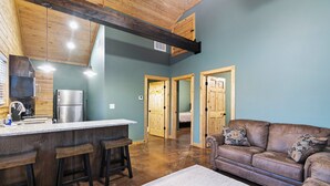 A kitchen with a bar area, wooden ceiling beams, and a blue wall.