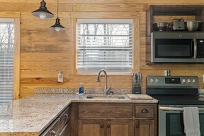 Una cocina con armarios de madera, encimera de granito, microondas de acero inoxidable y horno empotrado.