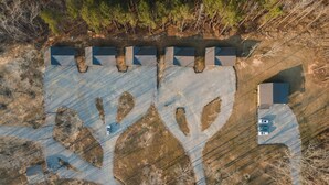 Vista aérea de una propiedad con varios edificios, una zona de estacionamiento y una fuente de agua.