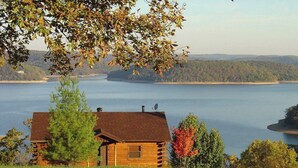 Una cabaña de troncos con vista a un lago y colinas distantes.