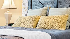 A bed with a grey and white duvet, two yellow knitted pillows, and a blue headboard. - Daily Double-Expo, UofL, Downtown, Highlands, close to track, NEW LISTING! (Louisville)