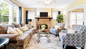 A living room with a sofa, armchair, and a fireplace. - Daily Double-Expo, UofL, Downtown, Highlands, close to track, NEW LISTING! (Louisville)