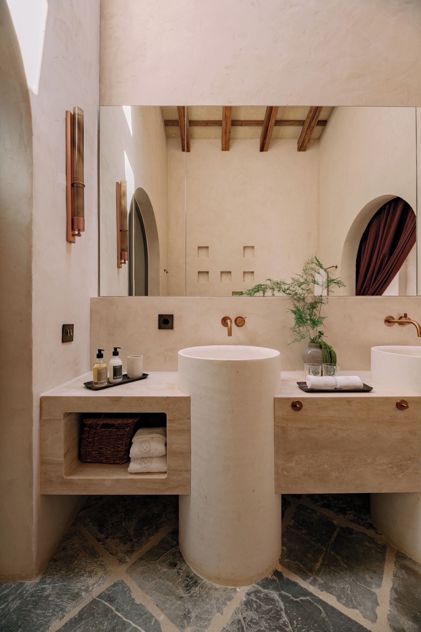 Un baño moderno con dos lavamanos, un espejo grande y una repisa de madera con toallas.