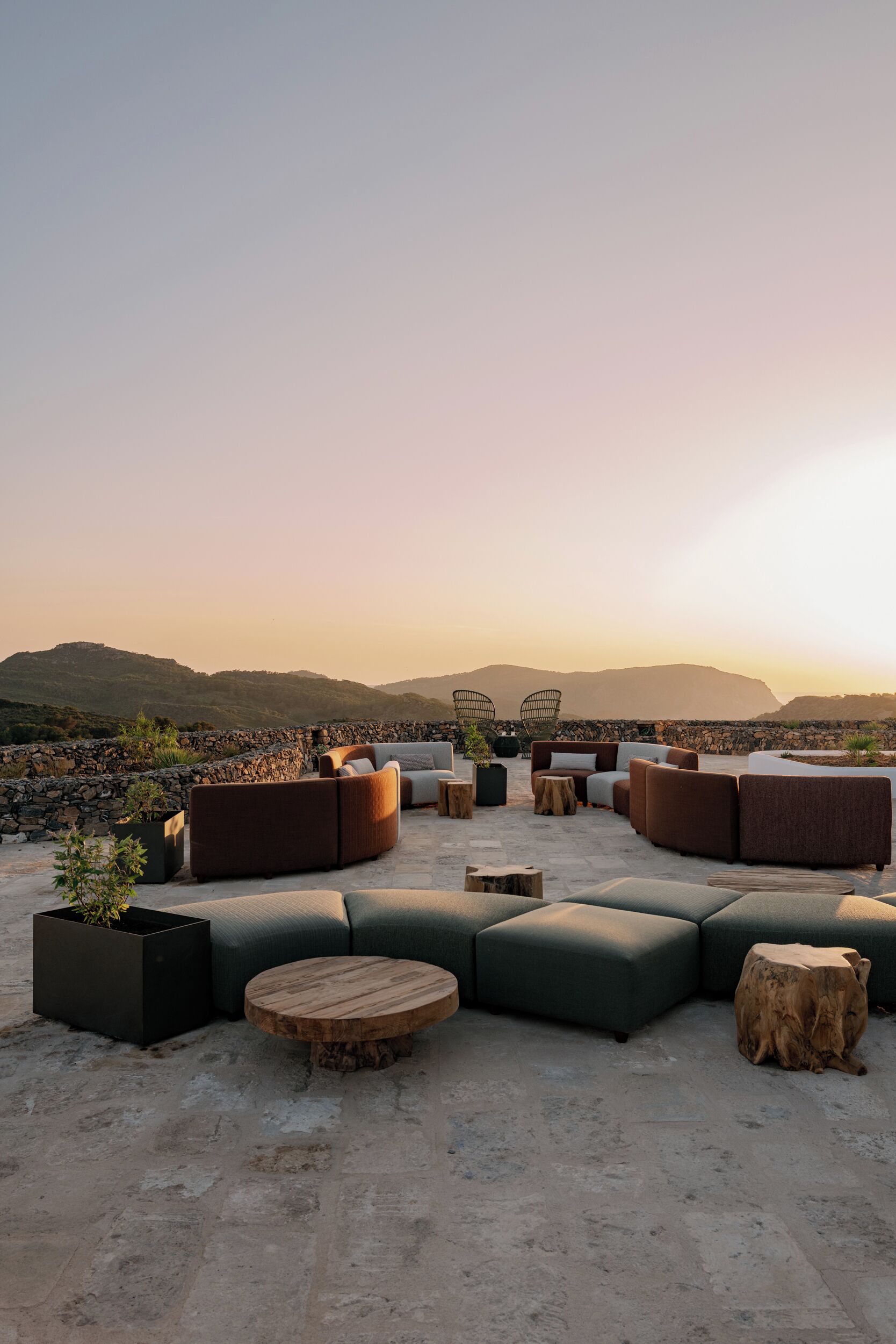 Terraza en la azotea con sofás modulares, mesas redondas y plantas en macetas.