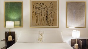 A hotel room with a bed, two bedside tables, and three framed artworks on the wall. - Les Suites del Carmine 3 by Wonderful Italy (Genoa)
