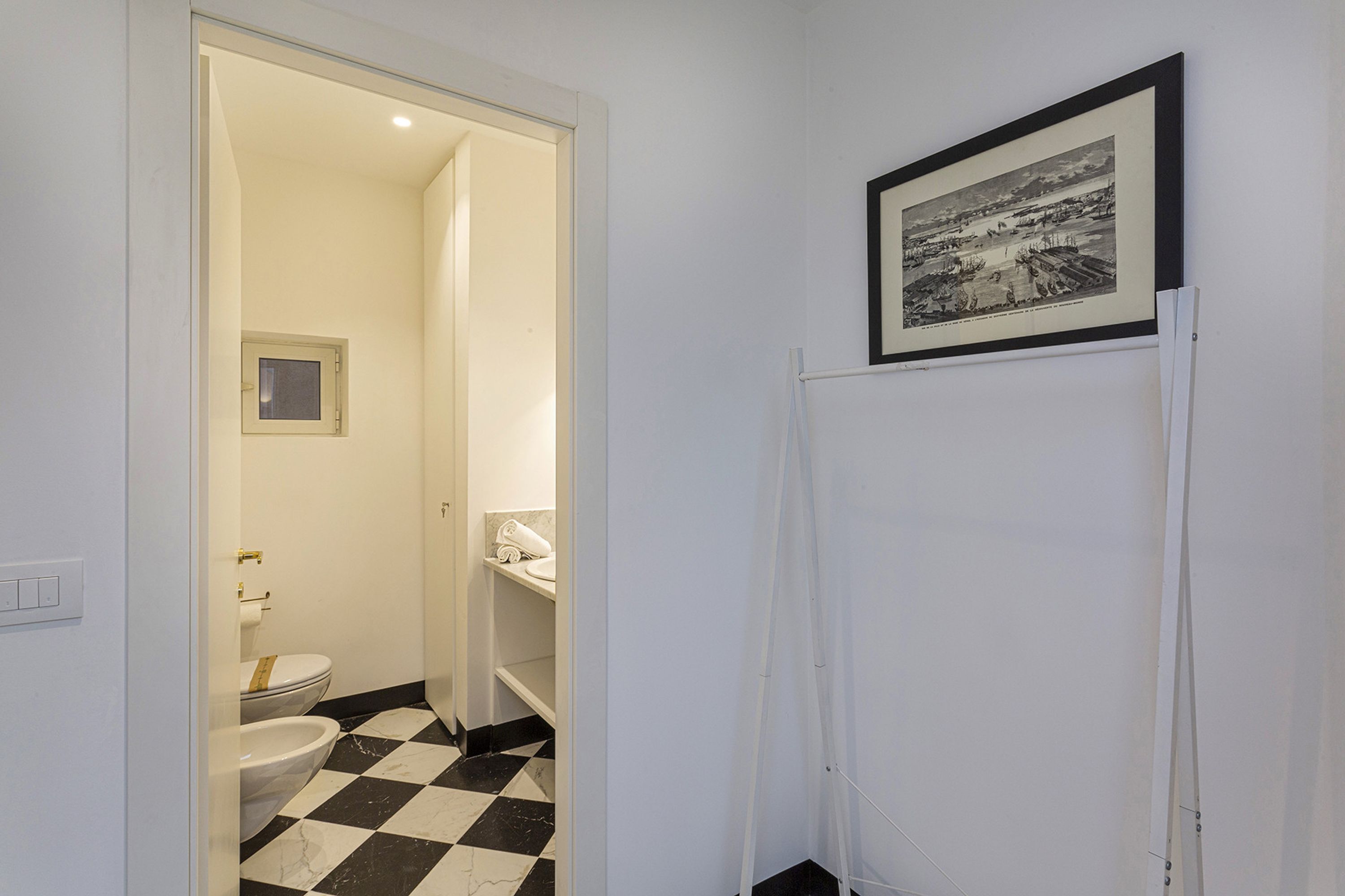 A bathroom with a checkered floor, a toilet, a sink, and a framed picture on the wall.