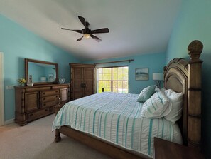 Relax in this serene bedroom with a large bed, wooden headboard, and dresser.