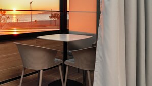 Un comedor moderno con vistas a la puesta de sol sobre el agua, que incluye una mesa y dos sillas.