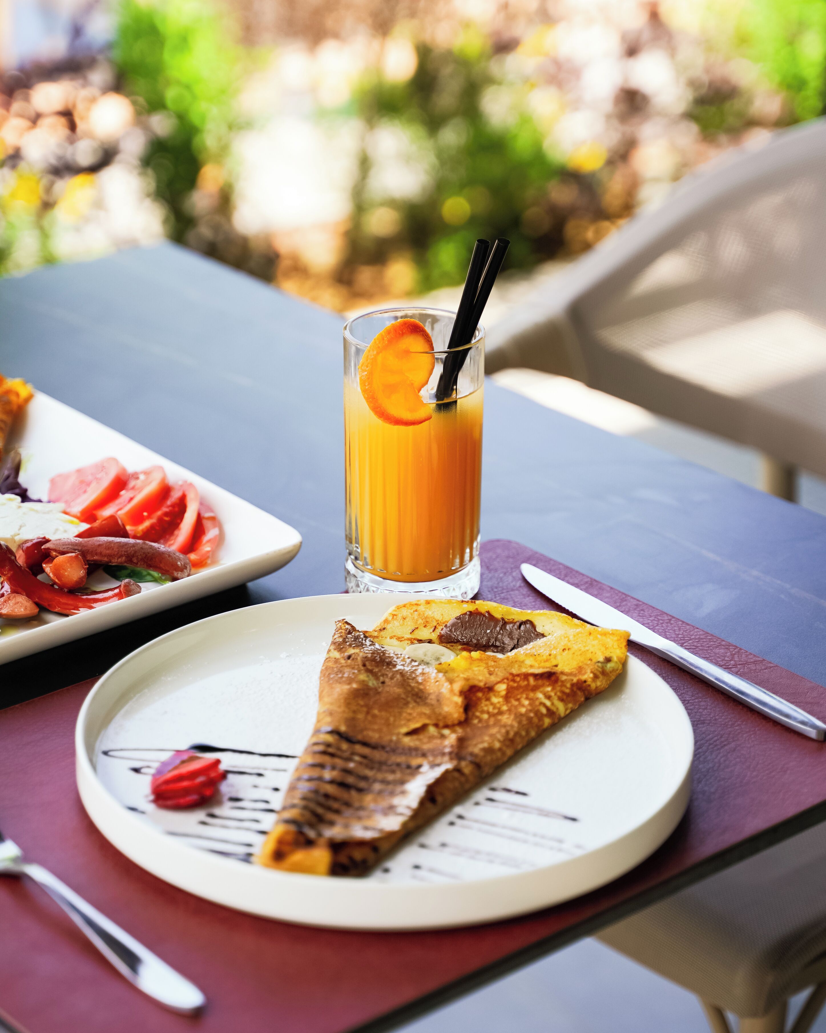 A breakfast setting with a plate of food, a glass of orange juice, and a knife on a table.
