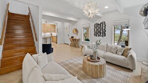 A spacious living area with a wooden staircase, a modern chandelier, and a view of the outdoors. - Beautiful French Country Villa wt Pool & Fire-pit in marvelous Austin (Austin)