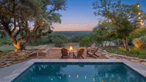 A pool with chairs and a fire pit, surrounded by trees and a clear view of the landscape. - Beautiful French Country Villa wt Pool & Fire-pit in marvelous Austin (Austin)