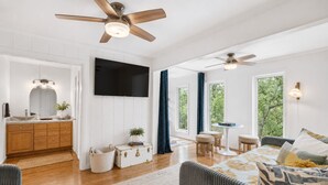 A spacious living area with a wooden floor, a sofa, a TV, and a ceiling fan. - Beautiful French Country Villa wt Pool & Fire-pit in marvelous Austin (Austin)