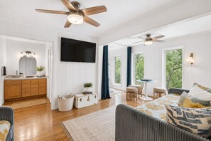 A spacious living area with a wooden floor, a sofa, a TV, and a ceiling fan. - Beautiful French Country Villa wt Pool & Fire-pit in marvelous Austin (Austin)