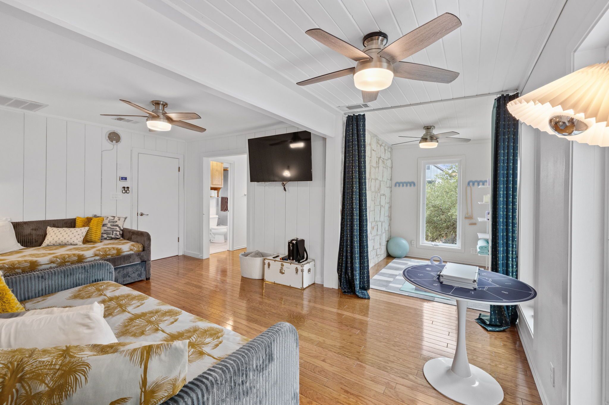 A spacious room with a ceiling fan, a flat-screen TV, a dining table, and a sofa.