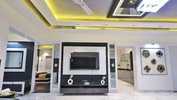 Een moderne woonkamer met een grote flatscreen televisie, een plafondventilator en decoratieve wandkunst.