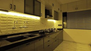 Een moderne keuken met een zwart aanrecht, roestvrijstalen apparatuur en een betegelde achterwand.