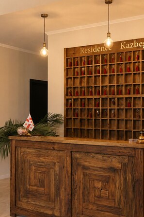 A reception desk with a wooden panel and a wall-mounted key rack. - Residence Kazbegi (Stepantsminda)