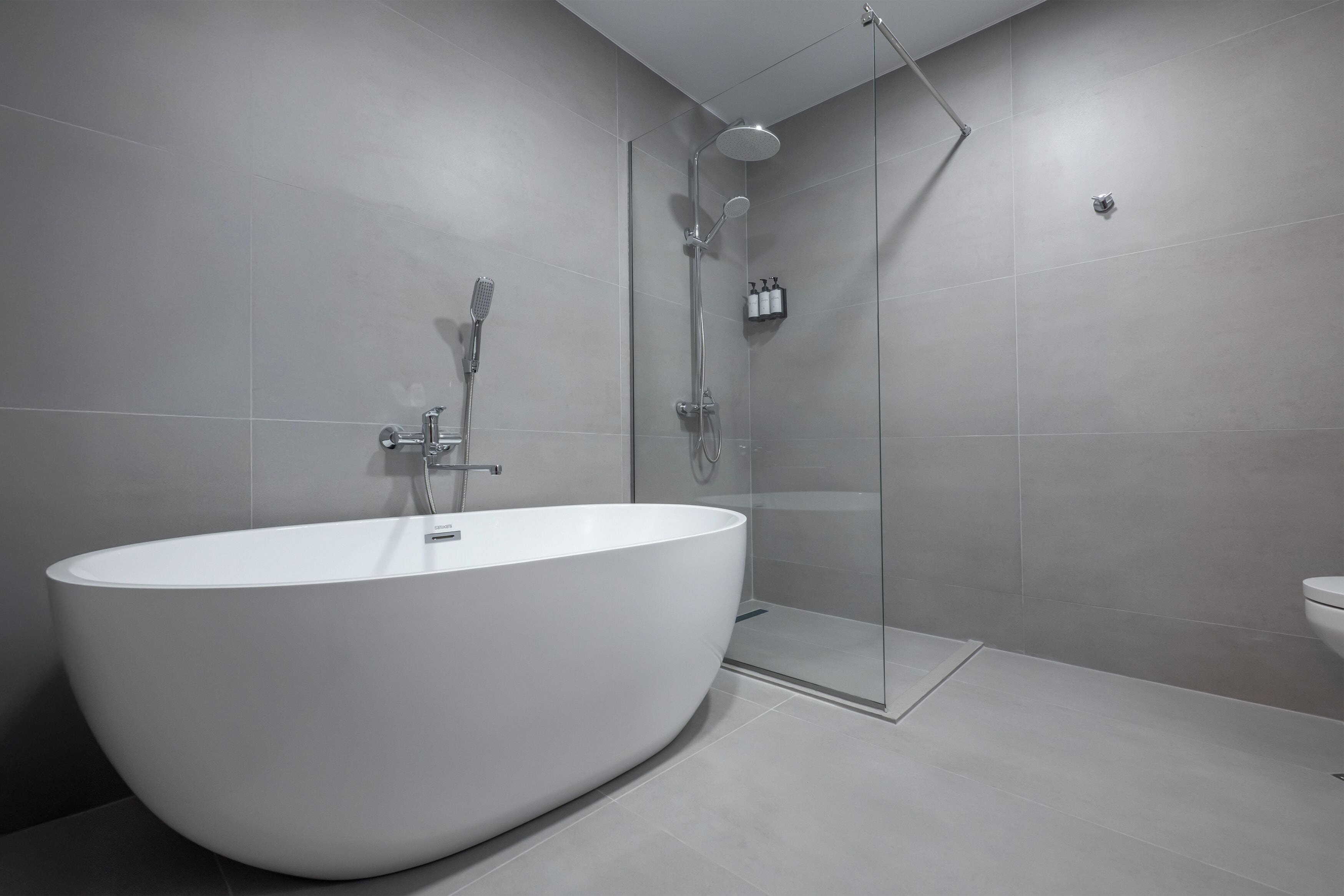 Ein modernes Badezimmer mit einer freistehenden Badewanne, einer gläsernen Duschkabine und einem WC.