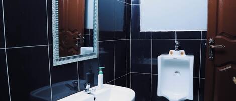 A bathroom with a white sink, a urinal, and a mirror with a decorative frame.