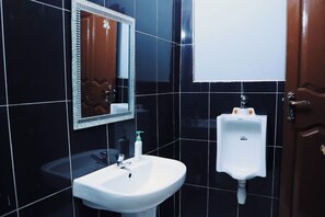 A bathroom with a white sink, a urinal, and a mirror with a decorative frame. - BUDDIEZ PLATINUM HOTEL (Kampala)
