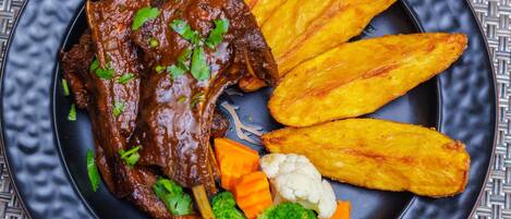A plate with beef, sweet potato fries, cauliflower, and carrots.