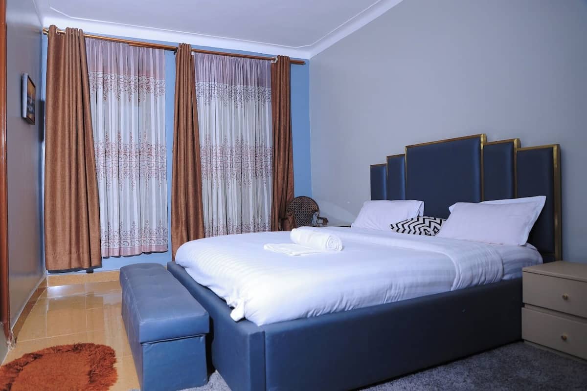 A modern bedroom with a large bed, a bedside table, a nightstand, and a bench.